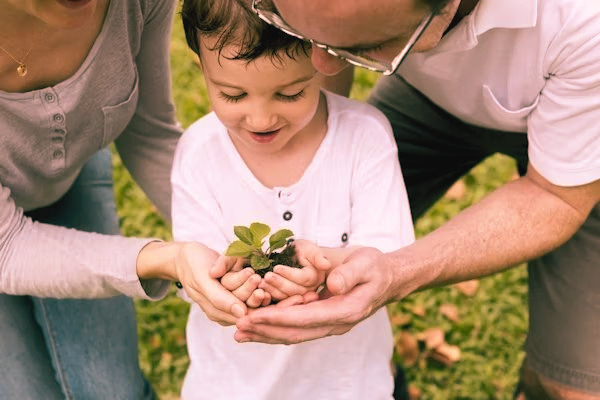 Familia sosteniendo un brote verde, símbolo de cuidado y crecimiento