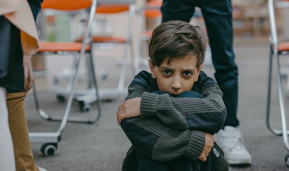 Niño con mirada triste y brazo cruzado en señal de aislamiento por estar sufriendo apego evitativo