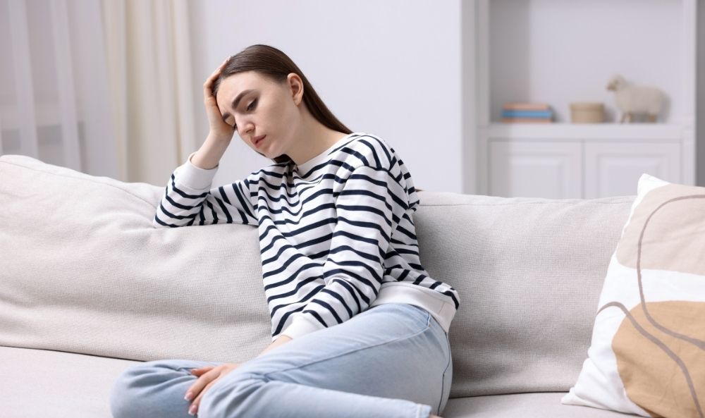 Mujer joven sentada en un sofá sufriendo los efectos secundarios de la terapia EMDR