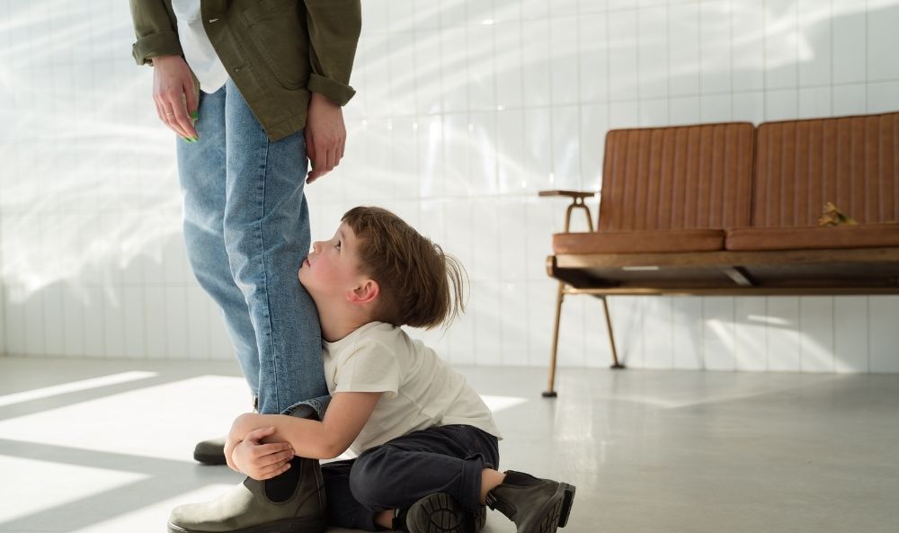 Niño tomando al padre de la pierna en señal de un tipo de apego inseguro